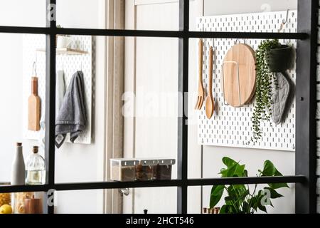 Peg boards with kitchenware hanging on light wall Stock Photo