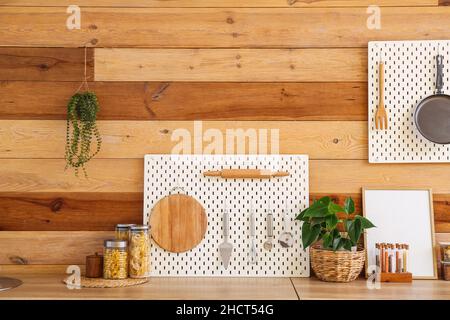 Peg board with kitchenware on kitchen counter near wooden wall Stock Photo