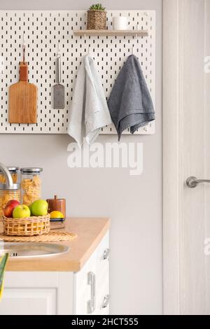 Peg board with kitchenware hanging on light wall Stock Photo