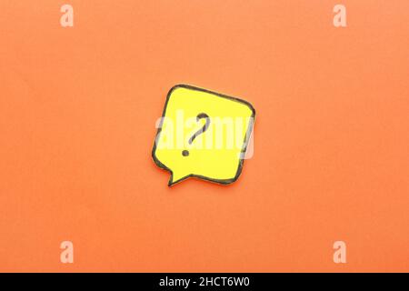 Sticky note in shape of speech bubble with question mark on orange background Stock Photo