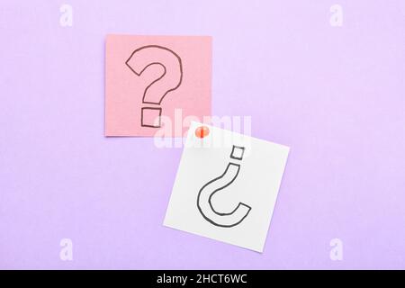 Sticky notes with question marks and pin on lilac background Stock Photo