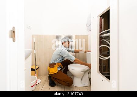 Plumber installing toilet in restroom Stock Photo