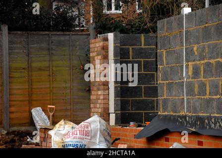 Building site with house under construction showing outer wall made of bricks and inner wall from breeze blocks with thick layer of insulation between Stock Photo