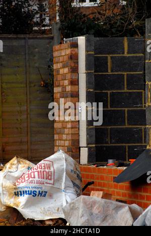 Building site with house under construction showing outer wall made of bricks and inner wall from breeze blocks with thick layer of insulation between Stock Photo