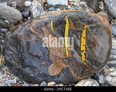 A closeup of a big rusty gold stone with rocks and pebbles in the background Stock Photo