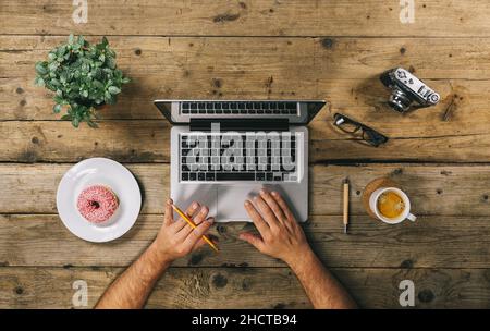 Hipster vintage wooden desktop top view, male hands typing on a laptop Stock Photo