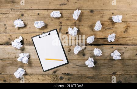 Clipboard with white sheet on wood background and Crumpled paper balls, with copyspace for your individual text. Stock Photo