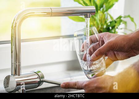 Filling glass of water from stainless steel kitchen faucet Stock Photo