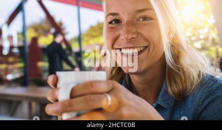 Beautiful smiling woman drinking coffee at cafe. Portrait of mature woman in a cafeteria drinking hot cappuccino and looking at camera. Pretty woman w Stock Photo