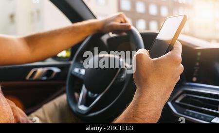 Man looking at mobile phone while driving a car Stock Photo