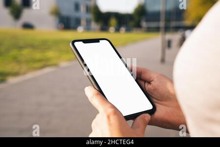 Mockup image of hands holding black mobile phone with blank desktop screen at summer in the city Stock Photo
