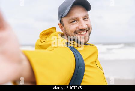 cheerful bearded young man solo traveler taking selfie at the beach - Adventure wanderlust concept on the beach Stock Photo