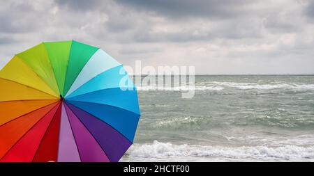 Colorful of umbrella on the beach and foam of sea waves at a thunderstorm, Weather concept image Stock Photo