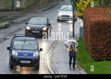 Chippenham, Wiltshire, UK. 1st January, 2022. With forecasters predicting that the uk could see the warmest New Year's Day ever, a woman is pictured walking in the rain as showers make their way across southern England. Credit: Lynchpics/Alamy Live News Stock Photo