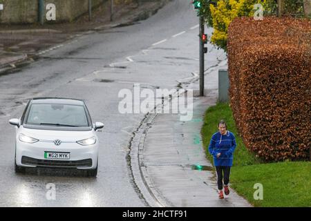 Chippenham, Wiltshire, UK. 1st January, 2022. With forecasters predicting that the uk could see the warmest New Year's Day ever, a woman is pictured running in the rain as showers make their way across southern England. Credit: Lynchpics/Alamy Live News Stock Photo