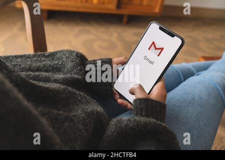 Woman holding a iPhone with Google Gmail app logo on the display. Gmail is a most popular free Internet e-mail service provided by Google. Stock Photo