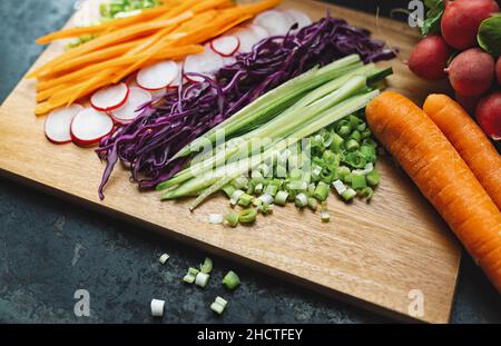 mixed vegetables ready to eat in slices on a wooden board, ready for summer rolls or rice paper rolls Stock Photo
