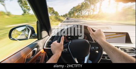 hands of car driver on steering wheel, road trip, driving on highway road Stock Photo