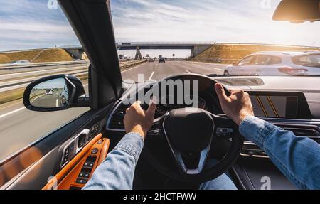 hands of car driver on steering wheel, road trip, driving on highway road Stock Photo