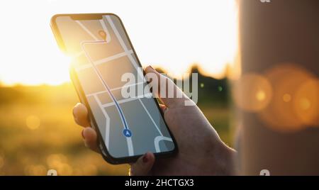 Tourist using GPS map navigation app on smartphone screen to get direction to destination address in the landscape, travel and technology concept imag Stock Photo