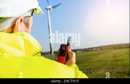 Engineer working a wind turbines, talking on the walkie-talkie for controlling work Stock Photo