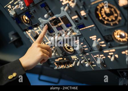 Close-up of a pilot's hand turning a toggle switch on the control panel. Stock Photo