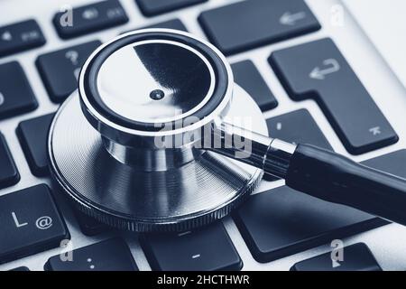 Silver stethoscope lying down on an notebook, blue toned Stock Photo