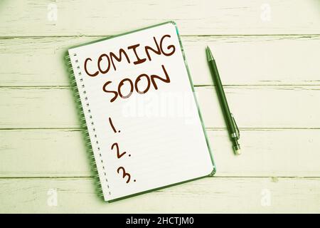 Sign displaying Coming Soon. Concept meaning an event that is bound to happen in the future or about to come Keyboard Over A Table Beside A Notebook Stock Photo