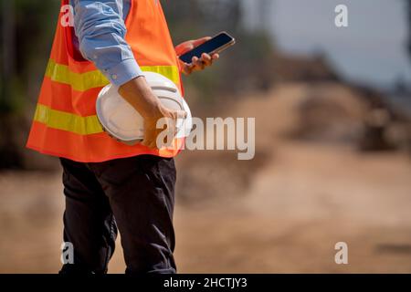 Man holding White helmet close up. Construction workers working on construction site.  Back side view Stock Photo
