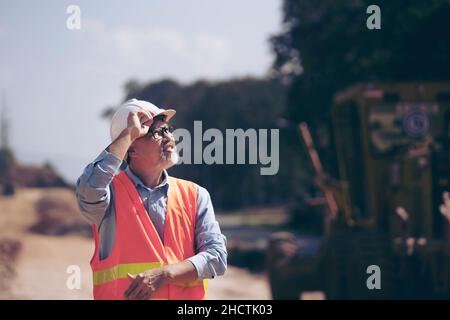 Surveyor builder Engineer technician  Business Team discuss plan at new construction site. Road construction machinery on the construction of highway. Stock Photo