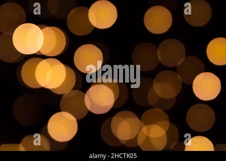 Christmas and Happy new year bokeh abstract lights in warm orange tones on blurred black background Stock Photo