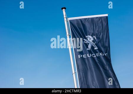 Peugeot logo on a flag against blue sky. Peugeot is a French cars brand, part of PSA Peugeot Citroen. Stock Photo