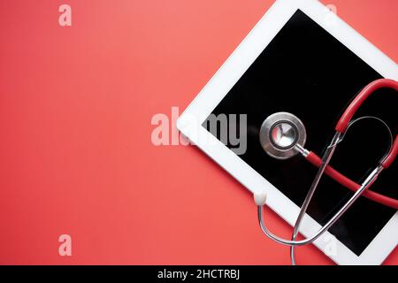 high angle view of digital tablet pen and stethoscope on red background  Stock Photo