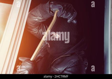Burglar trying to break into a house with a crowbar at night Stock Photo