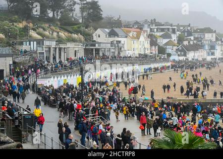 Lyme Regis, Dorset, UK.  1st January 2022.  UK Weather.  The seafront is packed at Lyme Regis in Dorset as visitors, locals and New Years Day revellers turn out to watch and take part in the annual charity Lyme Lunge swim on a day of overcast skies and unseasonably warm temperatures.  Picture Credit: Graham Hunt/Alamy Live News Stock Photo