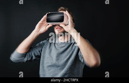 young man wearing Virtual Reality goggles VR Headset on black background Stock Photo