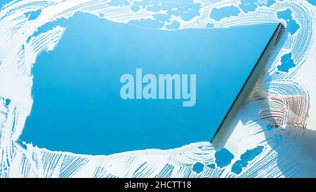Window cleaner using a squeegee to wash a window Stock Photo