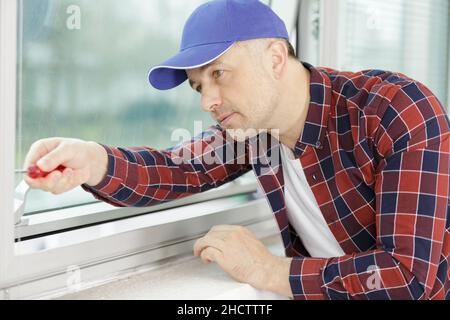 worker fasten the handle to a plastic window Stock Photo