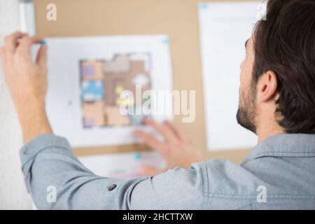 man putting a plan on a cork board Stock Photo