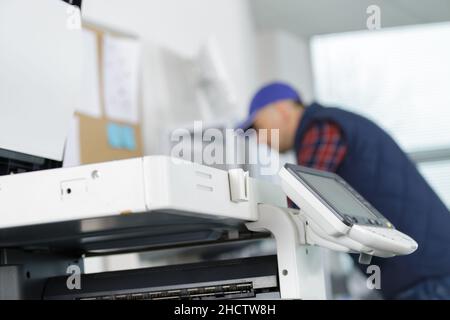 handyman blurred in the background behind a photocopier Stock Photo