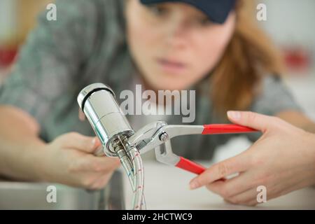 female plumber fixing a kitchen sink Stock Photo