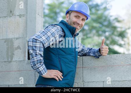 optimistic worker builder man posing showing thumb up Stock Photo