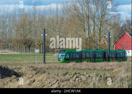 Lund, Sweden - April 10 2021: The new green electric tram moving in the rural parts of the town Stock Photo