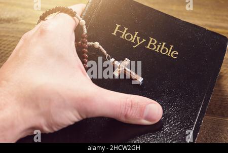 Hand holding Holy Bible with crucifix Stock Photo