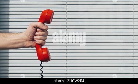 Red phone over office background concept for customer support line or important call Stock Photo