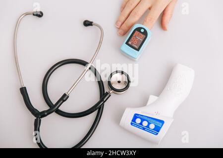 Stethoscope, pulse oximeter and thermometer gun on white background. Treatment of cold or flu. Phonendoscope. Infrared isometric thermometer gun to Stock Photo