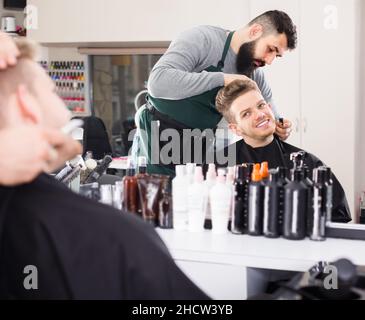 Man hairdresser making haircut to client Stock Photo