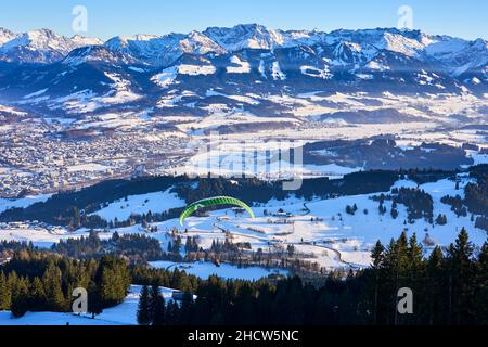 Sonthofen, Bavaria, Germany, 12-17-2021, paraglider starting from Mittag summit into the snowy landscape of Iller Valley near Sonthofen and Oberstdorf Stock Photo
