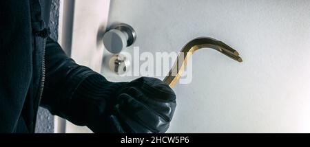 burglar with crowbar trying to bopens a house door Stock Photo