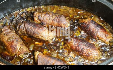 Closeup of isolated black metal casserole pot in oven with typical german fresh homemade beef roulades in sauce Stock Photo